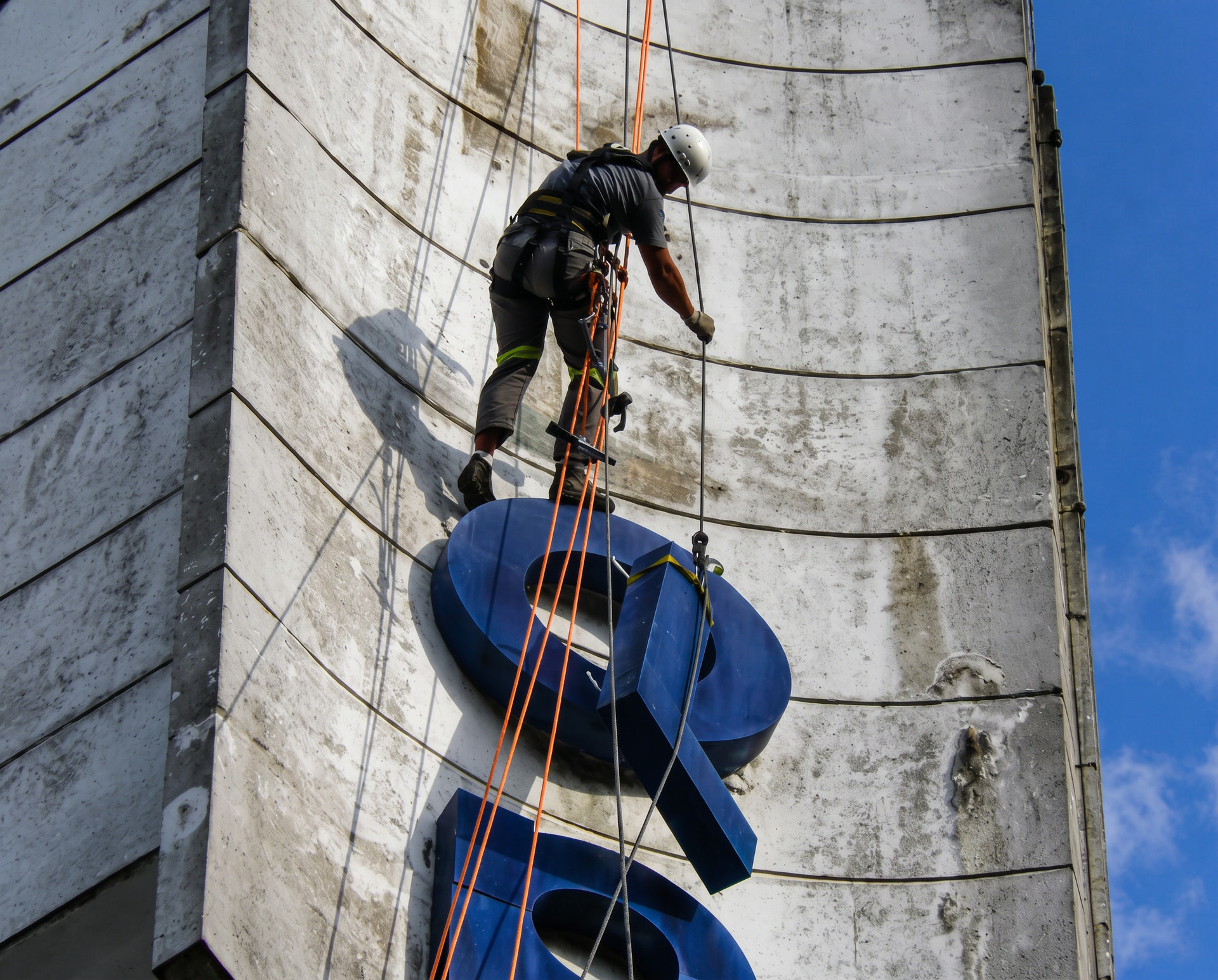 Profissional da MS Alpinismo instalando letreiro em altura